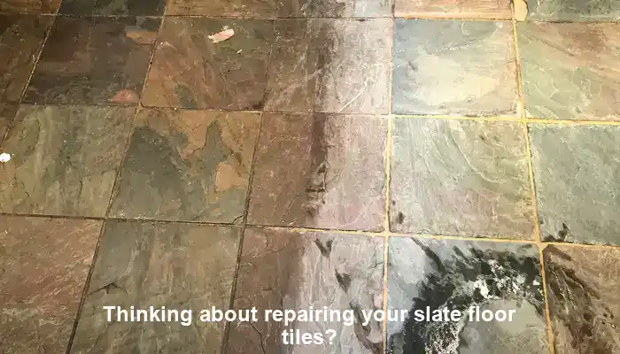Cracked slate floor tiles with worn patches necessitating repair assessment